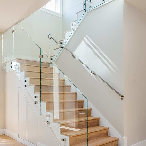 Modern staircase with wooden steps, glass balustrades, and white walls in a bright, well-lit interior space, ideal for real estate sellers.
