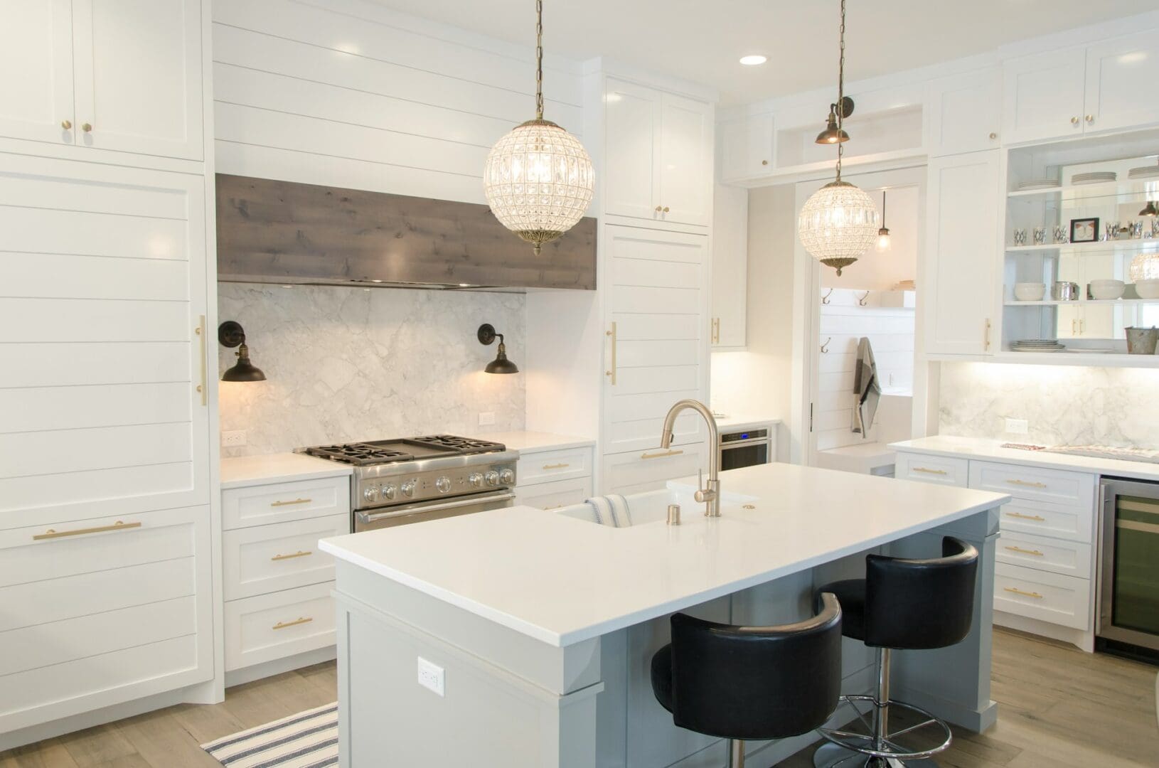 Modern kitchen with white cabinets, marble backsplash, central island with bar stools, and pendant lighting, perfect for real estate sellers.